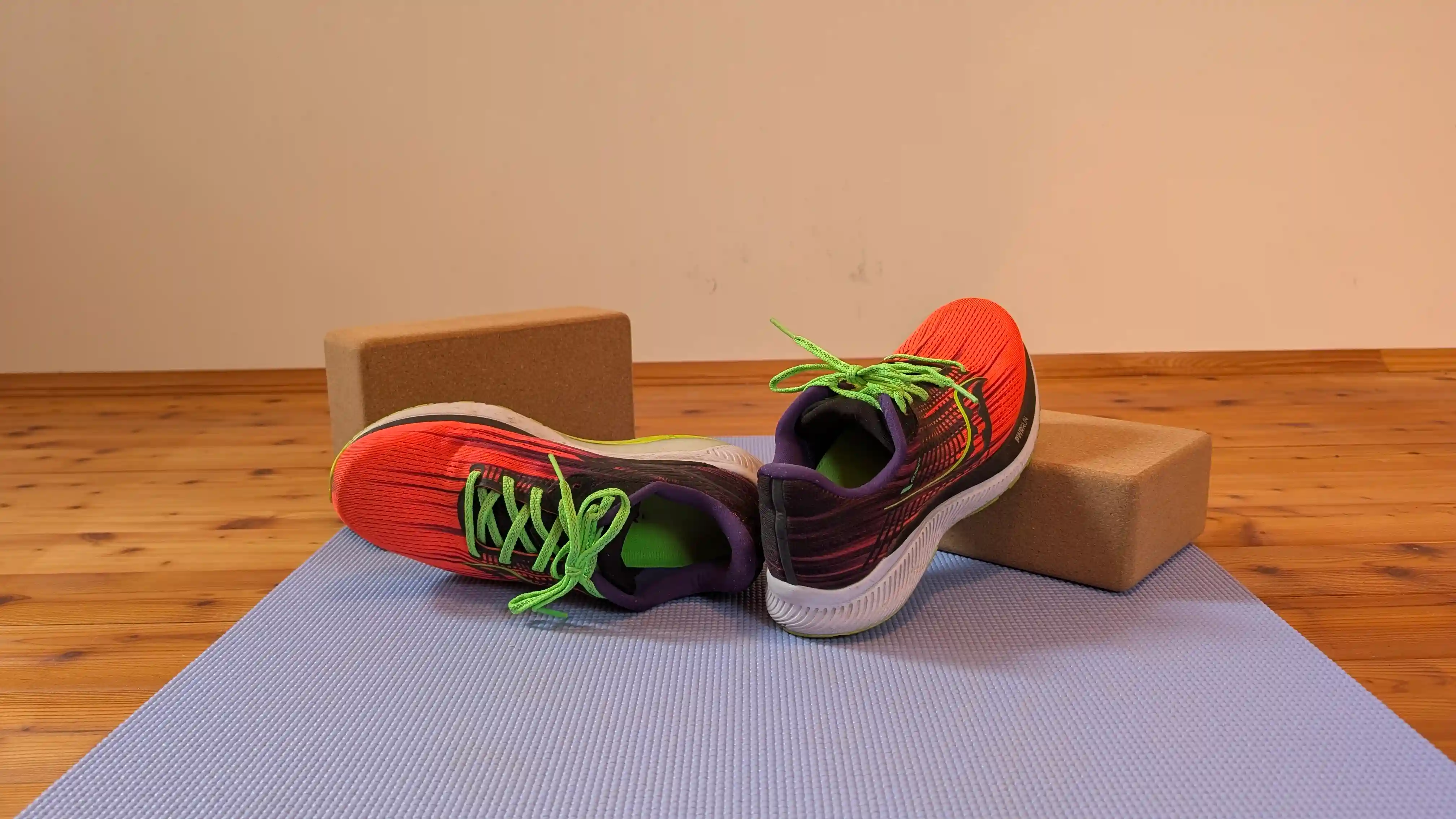 Laufschuhe und Yogablöcke liegen auf einer Yogamatte.