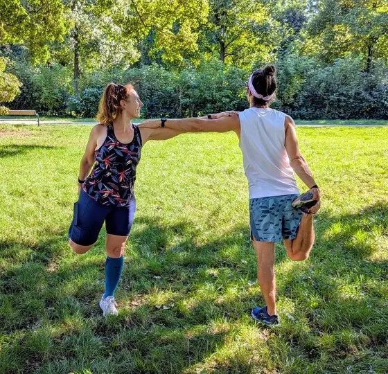 Marion und ein Kunde beim Dehnen auf einer Wiese.